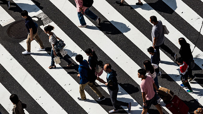 Menschen überqueren Straße auf Zebrastreifen