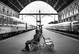 Auf einer Bank sitzender Mann am Bahnhof