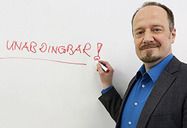 Wolfram Schaffar schreibt "Unabdingbar" auf eine Tafel