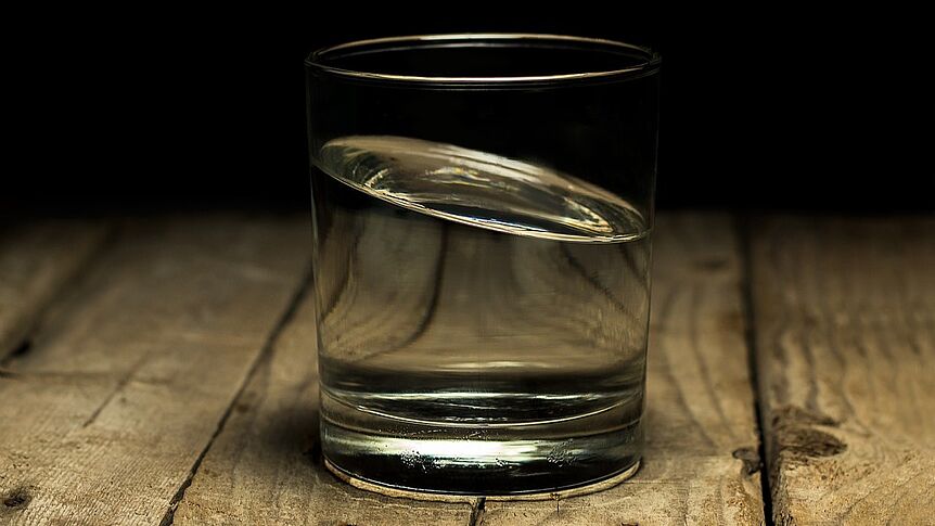 Glas mit Wasser auf Holzplatte