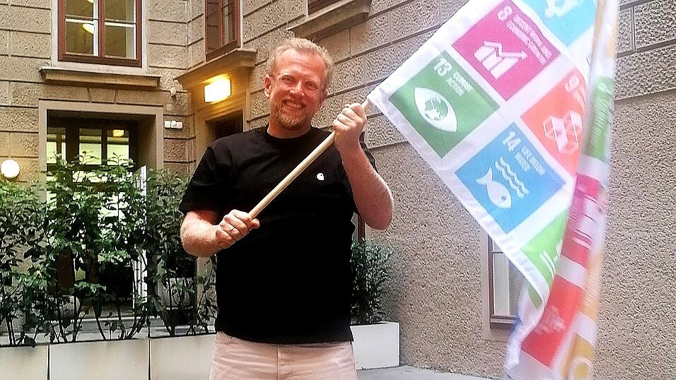 Kommunikationswissenschaftler Hajo Boomgaarden mit der SDG Flagge